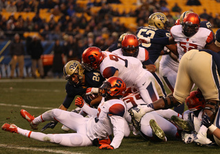 Conner is dragged down by SU defensive end Robert Welsh while linebacker Dyshawn Davis has the ball-carrier's legs.